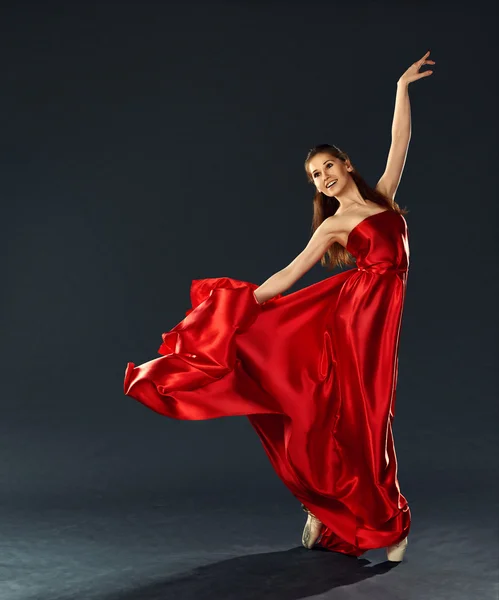 Beautiful ballerina dancing a long red dress flying — Stock Photo, Image