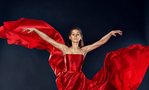Όμορφη εμπνευσμένη γυναίκα, χορό σε ένα ιπτάμενο κόκκινο μεταξωτό φόρεμα — Φωτογραφία Αρχείου