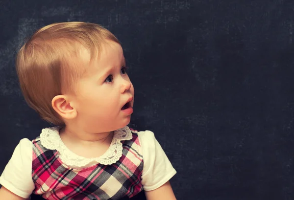 Frightened baby girl pupil with chalk at a school board — Stock Photo, Image