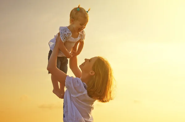 Happy family. Mother throws up baby in the sky at sunset — Stock Photo, Image