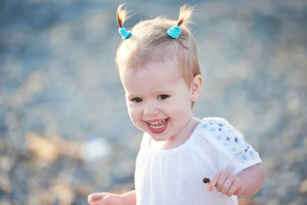 Gelukkig babymeisje met twee staart kapsel glimlachen op zee op de worden — Stockfoto