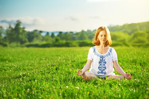 Jeune femme faisant du yoga sur herbe verte — Photo