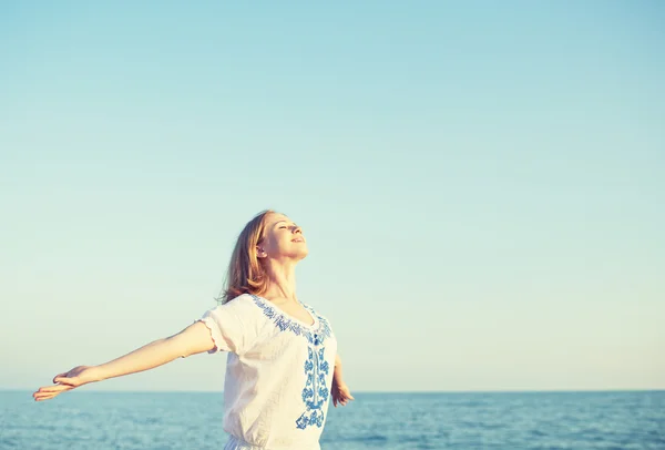 Glückliche junge Frau öffnet ihre Arme zum Himmel und Meer — Stockfoto