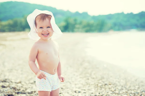 Glückliches kleines Mädchen mit Hut am Strand — Stockfoto