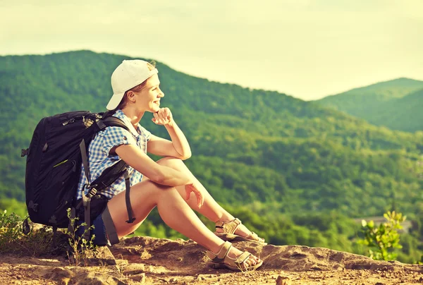 Turista donna con uno zaino seduto, poggiata su una cima di montagna — Foto Stock