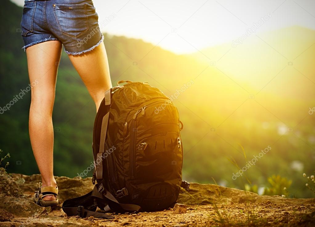 legs of a woman tourist and travel backpack on a mountain top