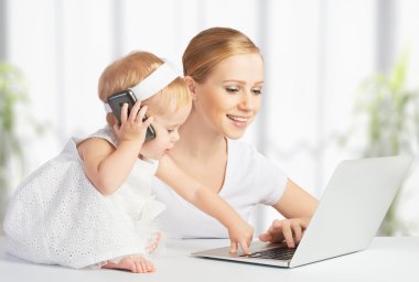 Anne bebek kızı ile bir bilgisayar ve telefon ile çalışır