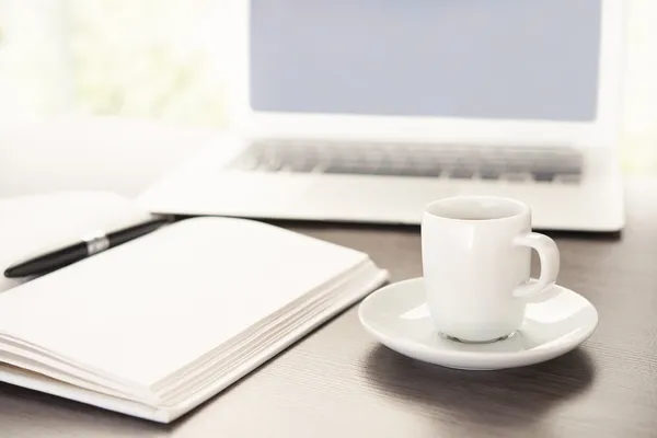 Escritorio con una taza de café ordenador portátil, portátil, pluma —  Fotos de Stock