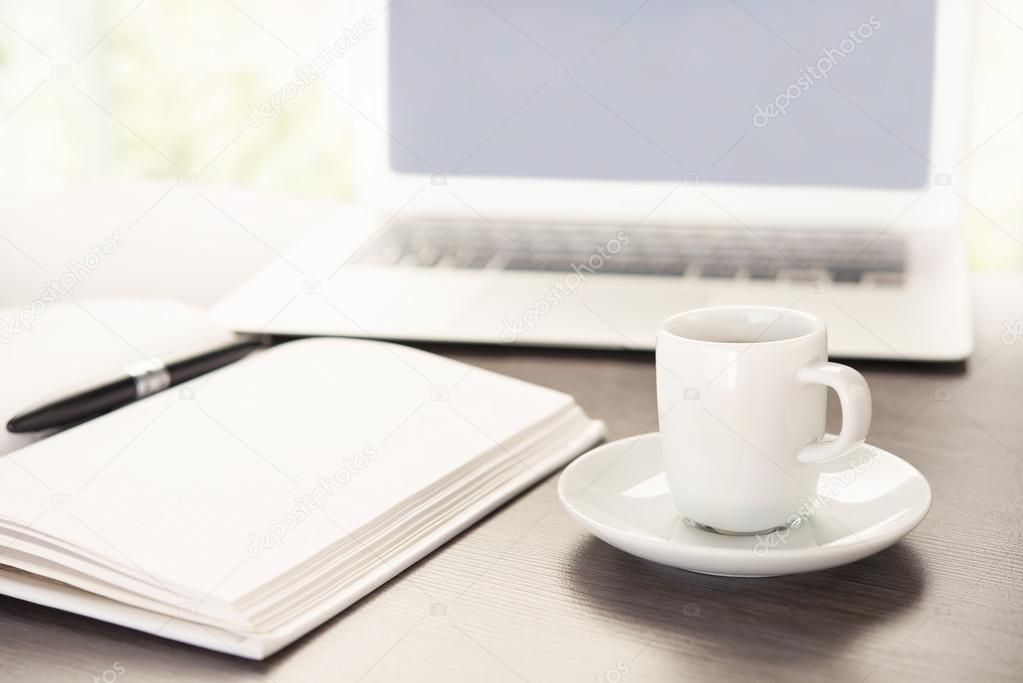 work desk with a cup of coffee computer laptop, notebook, pen