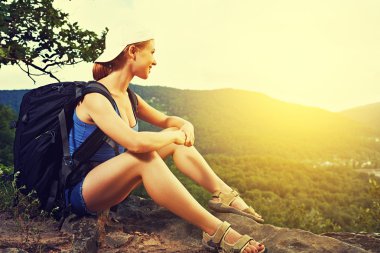 kadın turist ile oturmuş, dağın tepesinde bir kayaya yolculuğu dinlenme sırt çantası