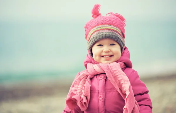 Gelukkig babymeisje in roze muts en sjaal lacht — Stockfoto