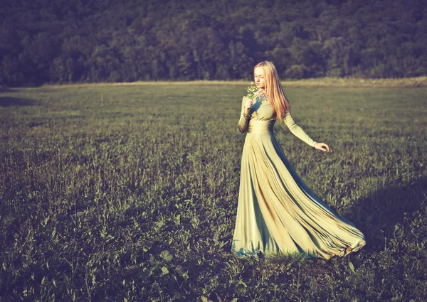 Schönes Mädchen im langen grünen Kleid mit Blumenstrauß im Sommer — Stockfoto