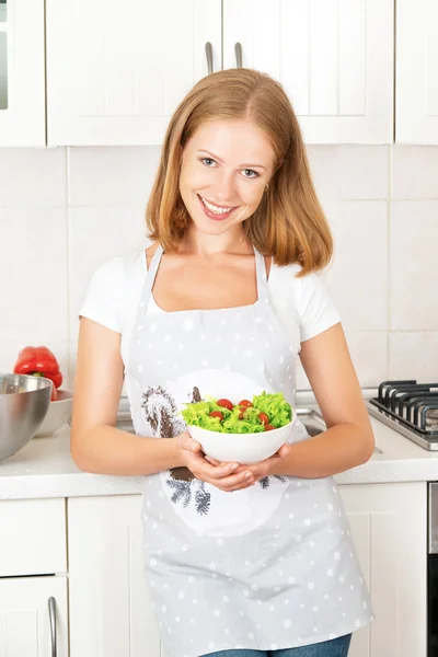 Gelukkig meisje met een plantaardige salade in de keuken — Stockfoto