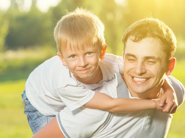 Feliz papá e hijo abrazando y riendo en la naturaleza de verano —  Fotos de Stock