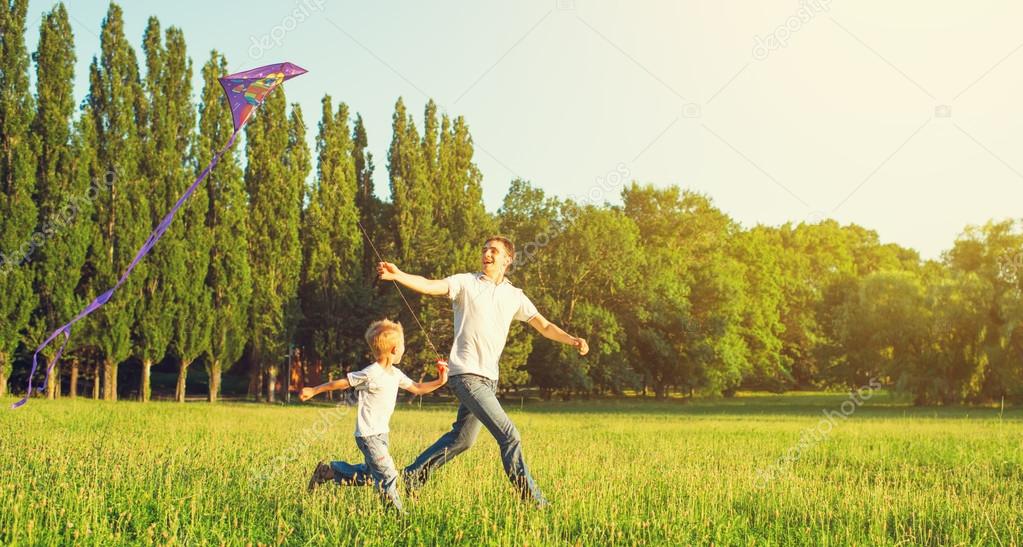 Dad and son child flying a kite in summer nature