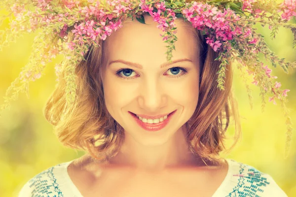 Vacker glad slavisk flicka i en krans av sommarblommor — Stockfoto