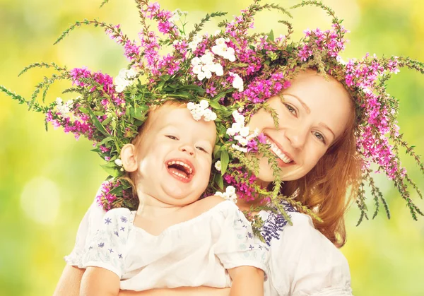 Happy laughing daughter hugging mother in wreaths of summer flowers — Stock Photo, Image