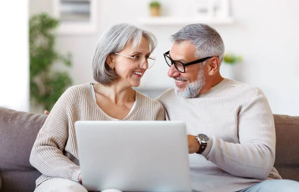 Feliz pareja de ancianos de la familia viendo la comedia o el vídeo divertido en el ordenador portátil, mientras que pasar tiempo libre en casa — Foto de Stock