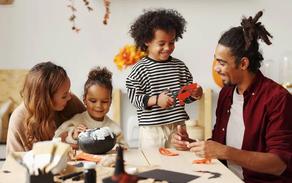 Joven familia afroamericana alegre madre, padre y dos niños preparándose para Halloween en casa —  Fotos de Stock