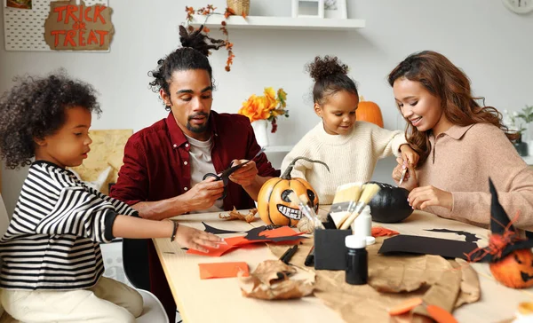 Joven familia afroamericana alegre madre, padre y dos niños preparándose para Halloween en casa —  Fotos de Stock