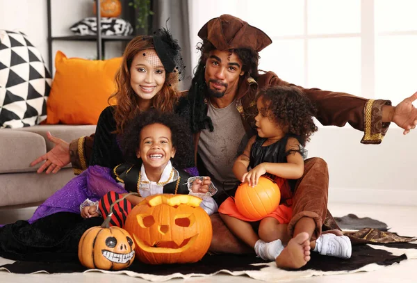 Afroamerikanische Familie in Halloween-Kostümen macht gruselige Geste, während sie mit Jack o Laterne sitzt — Stockfoto