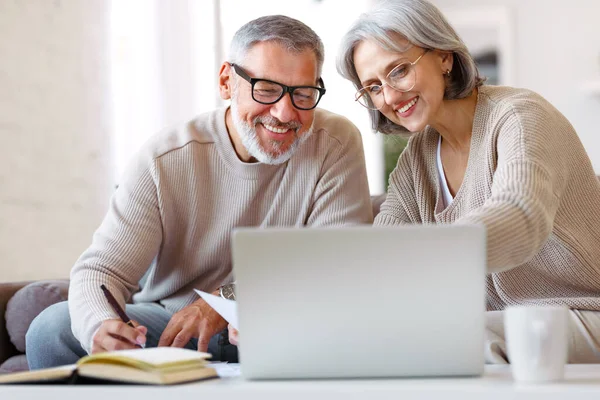Χαμογελαστό ηλικιωμένο ζευγάρι διαβάζει επιστολή κοινοποίησης με καλά νέα από την τράπεζα, ενώ κάθεται με φορητό υπολογιστή — Φωτογραφία Αρχείου