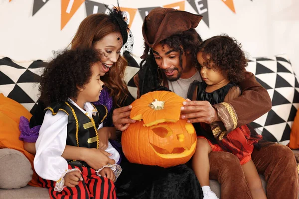 Heyecanlı aile babaları ve çocuklar Cadılar Bayramı kostümleri içinde Jack O Lantern 'in içine bakıyor. — Stok fotoğraf