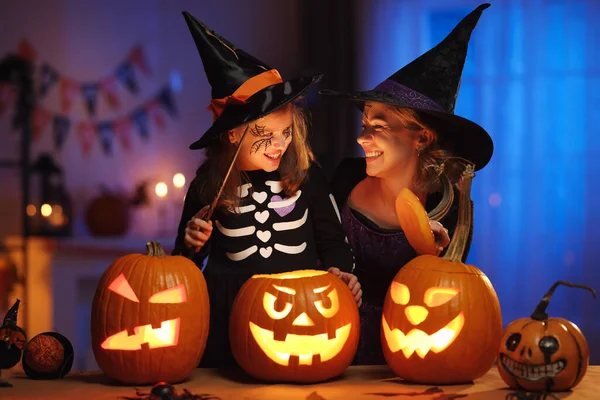 Ευτυχισμένη οικογένεια μητέρα και κοριτσάκι με κοστούμια μαγισσών γιορτάζοντας το Halloween στο σπίτι — Φωτογραφία Αρχείου