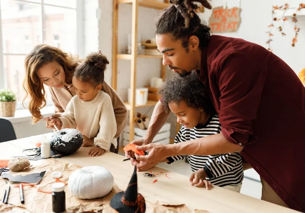 Joven familia afroamericana alegre madre, padre y dos niños preparándose para Halloween en casa —  Fotos de Stock