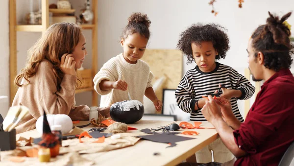 Joven familia afroamericana alegre madre, padre y dos niños preparándose para Halloween en casa —  Fotos de Stock
