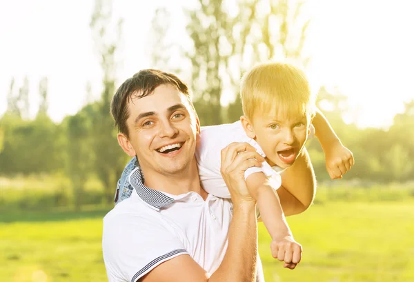 Feliz papá e hijo abrazando, jugando y riendo en la naturaleza de verano —  Fotos de Stock