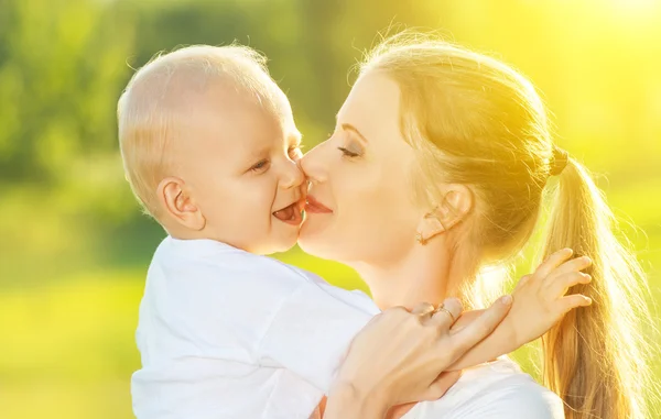 Happy family in summer. mother kissing her baby — Stock Photo, Image