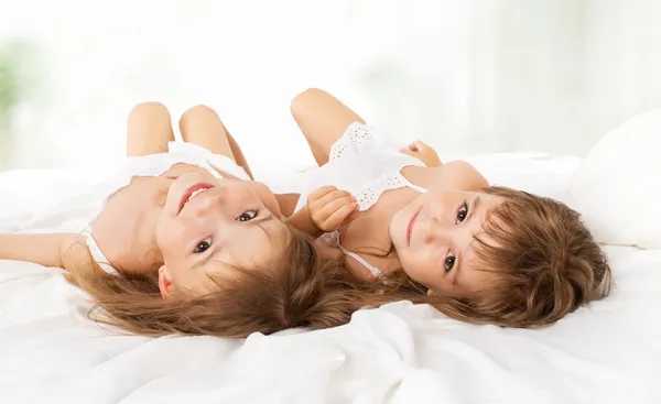 Niños felices niñas hermanas gemelas en la cama —  Fotos de Stock