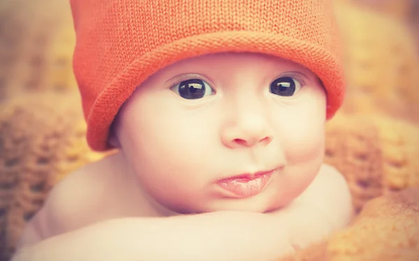 Милый новорожденный ребенок в вязаной оранжевой шляпе — стоковое фото