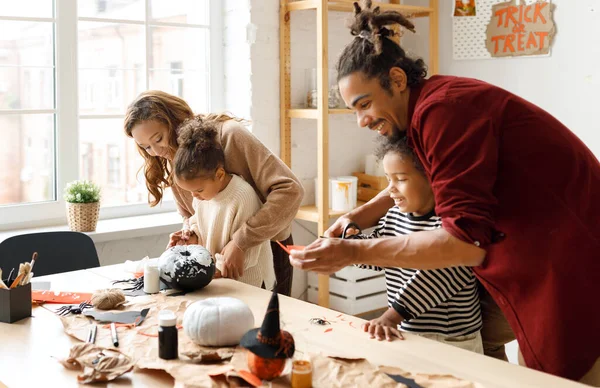 Joven familia afroamericana alegre madre, padre y dos niños preparándose para Halloween en casa —  Fotos de Stock