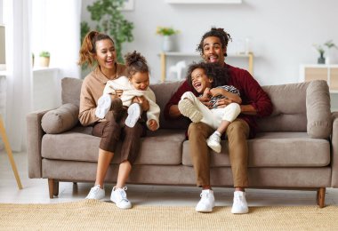 Neşeli Afro-Amerikan aile ve iki küçük çocuk evde birlikte eğleniyorlar.
