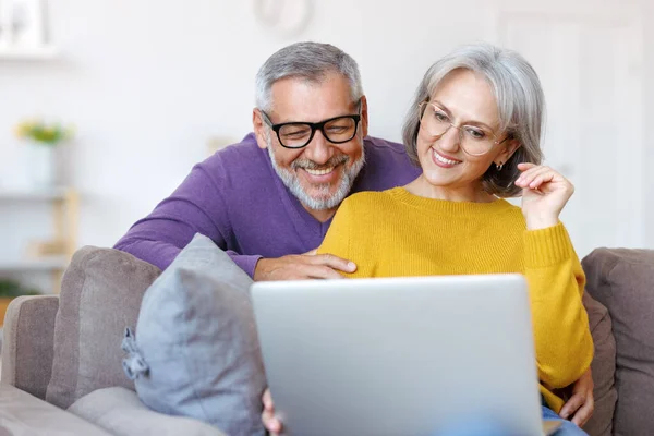 Όμορφο ώριμο οικογενειακό ζευγάρι κοιτάζοντας φορητό υπολογιστή με χαμόγελο στο πρόσωπο, ενώ περνούν το χρόνο τους μαζί — Φωτογραφία Αρχείου