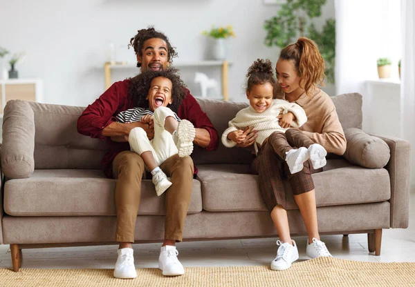 Радостные африканские американские родители и двое маленьких детей, веселящихся вместе дома — стоковое фото