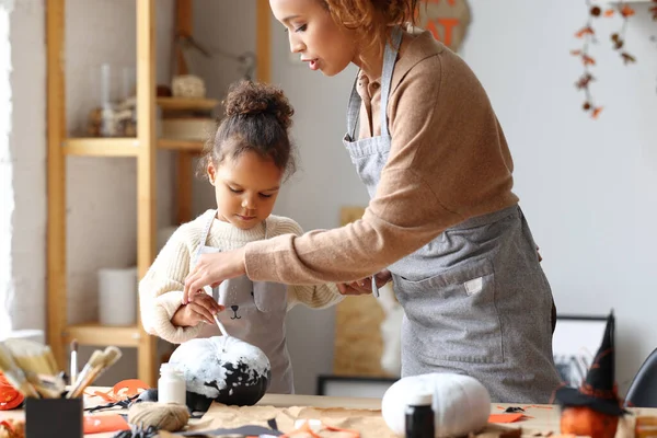 Linda niña afroamericana pintando calabaza de Halloween con mamá juntos en casa — Foto de Stock