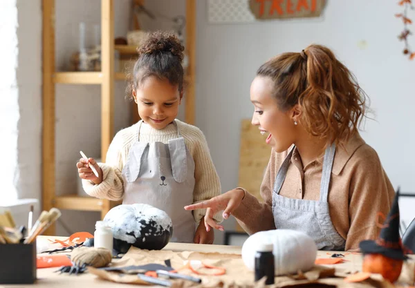 Carino poco africano americano ragazza pittura halloween zucca con mamma insieme a casa — Foto Stock