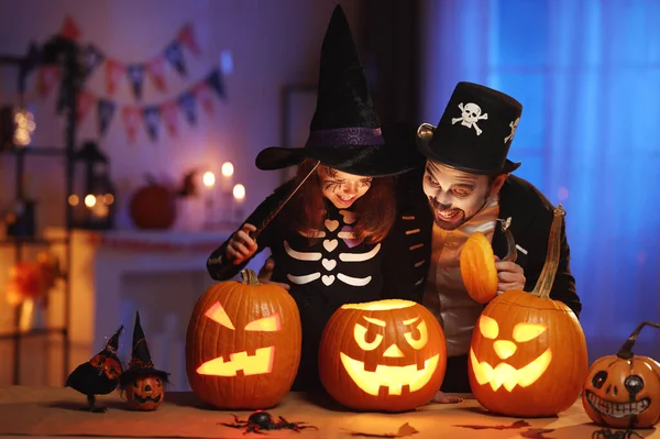 Happy family father and daughter in Halloween costumes looking inside of glowing jack-o-lantern — Stock Photo, Image