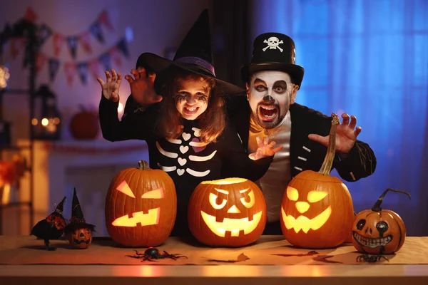 Happy family father and daughter in Halloween costumes with glowing jack-o-lantern celebrating all hallows eve at home — Stock Photo, Image