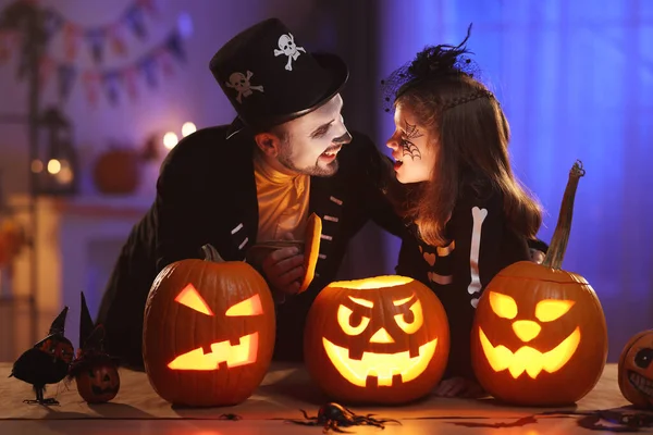 Feliz familia padre e hija en disfraces de Halloween con brillante jack-o-linterna — Foto de Stock