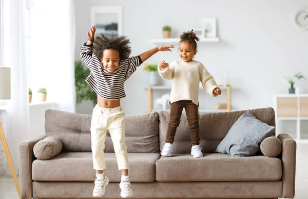 快乐精力充沛的非洲裔美国孩子们跳到沙发上 — 图库照片