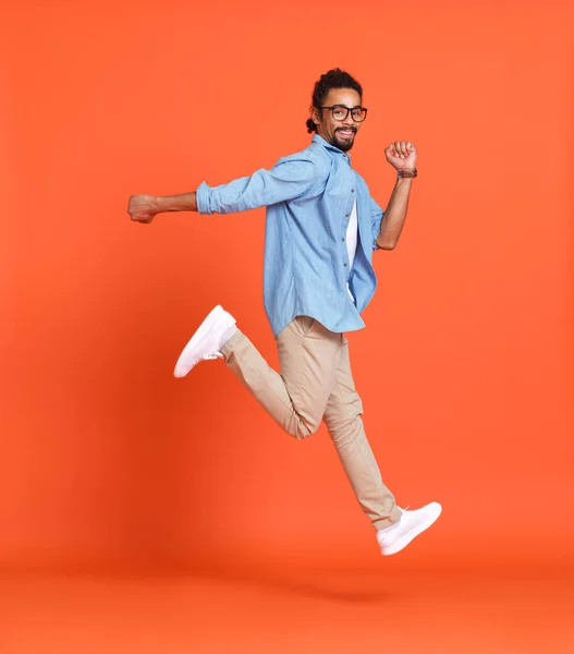 Corpo inteiro foto de feliz louco afro-americano cara pulando isolado sobre fundo laranja — Fotografia de Stock