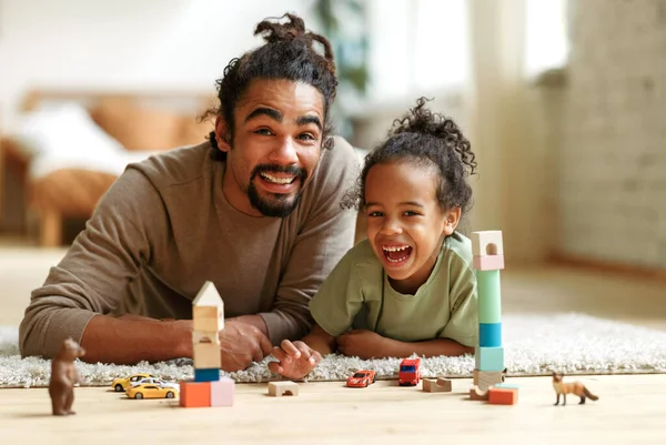 幸せなアフリカ系アメリカ人の家族の父と子供の息子は家で一緒におもちゃをプレイしながら笑う — ストック写真