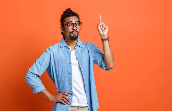 Jonge serieuze Afro-Amerikaanse man in casual kleding wijzen naar kopieerruimte met wijsvinger — Stockfoto