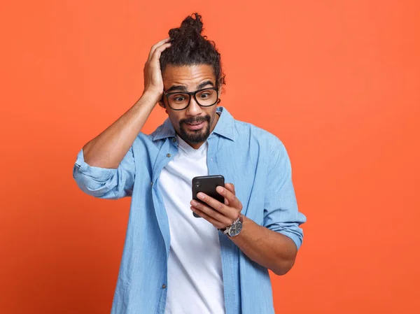 충격을 받은 젊은 아프리카 계 미국인 남자가 얼굴 표정으로 스마트폰을 보고 있는 것을 보고 깜짝 놀랐습니다. — 스톡 사진