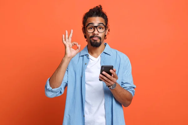 Studio isolé tourné de jeune homme afro-américain montrant ok signe avec téléphone portable à la main — Photo