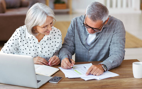 Старшая счастливая семейная пара делает домашнее задание вместе во время учебы онлайн на ноутбуке дома